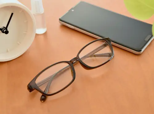 机に置かれたメガネとスマホ