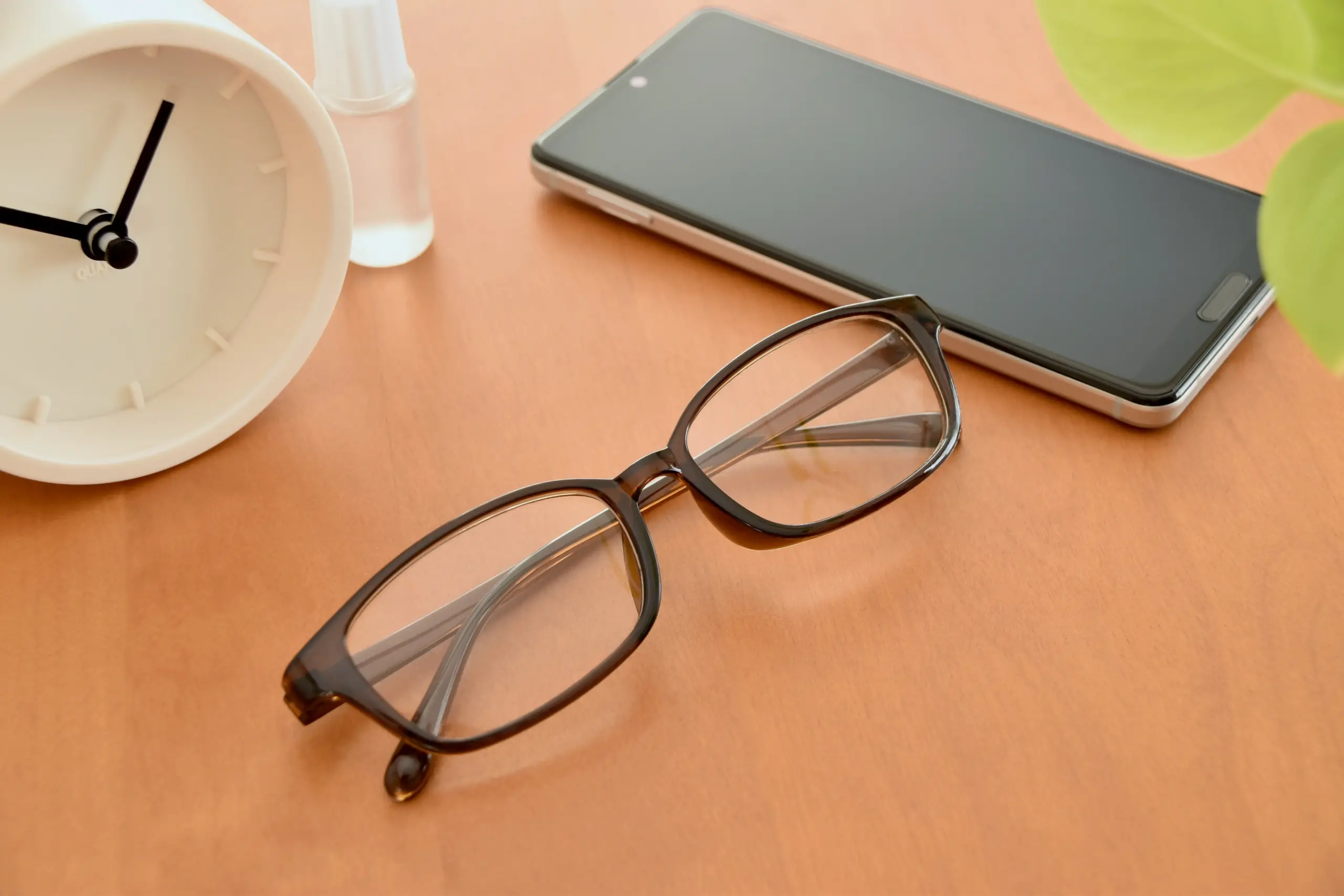 机に置かれたメガネとスマホ