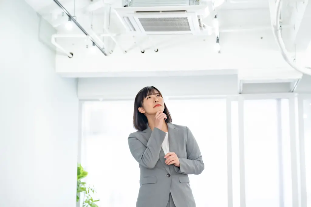 オフィスのエアコンを見上げる女性