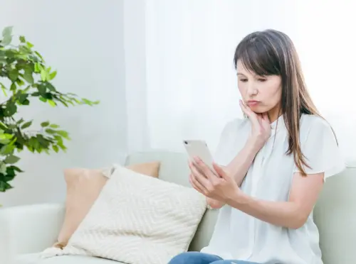 スマホを見て悩む女性