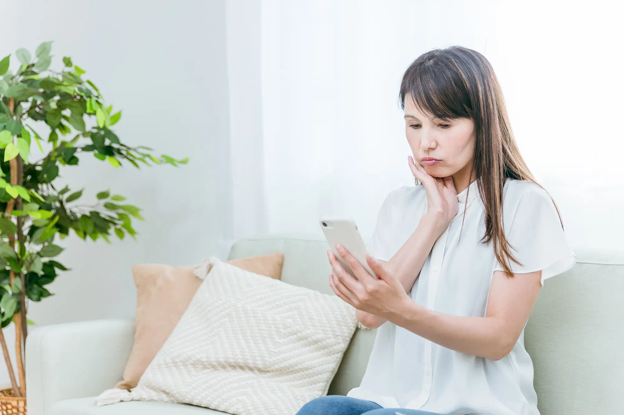 スマホを見て悩む女性