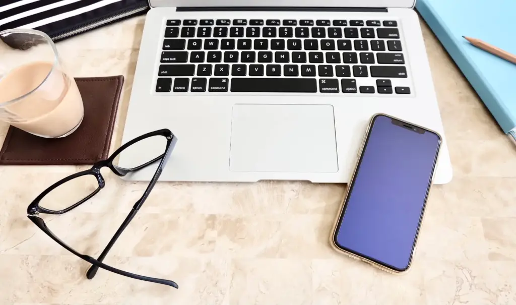 机に置かれたパソコンとスマホとメガネ
