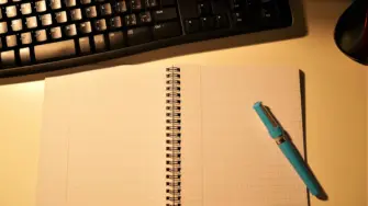 パソコンとノートを置いたデスクを照らすデスクライト