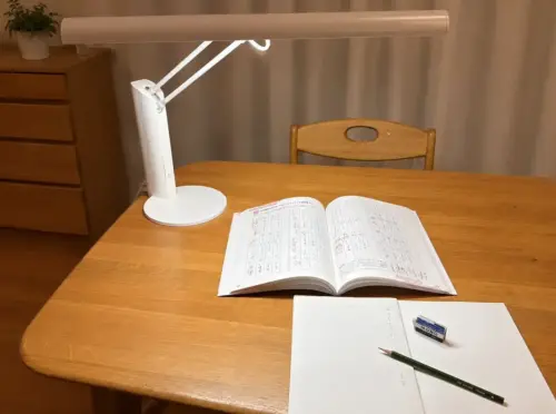 デスクライトで教科書とノートを照らした学習机